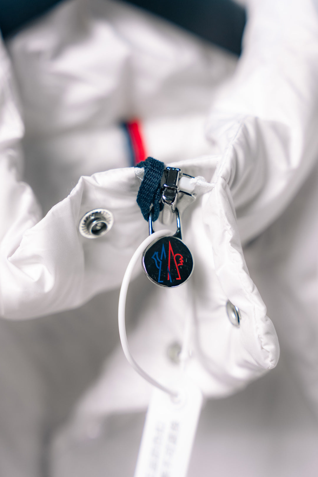 White puffer jacket sleeve cuff with snap button and hanging Moncler tag