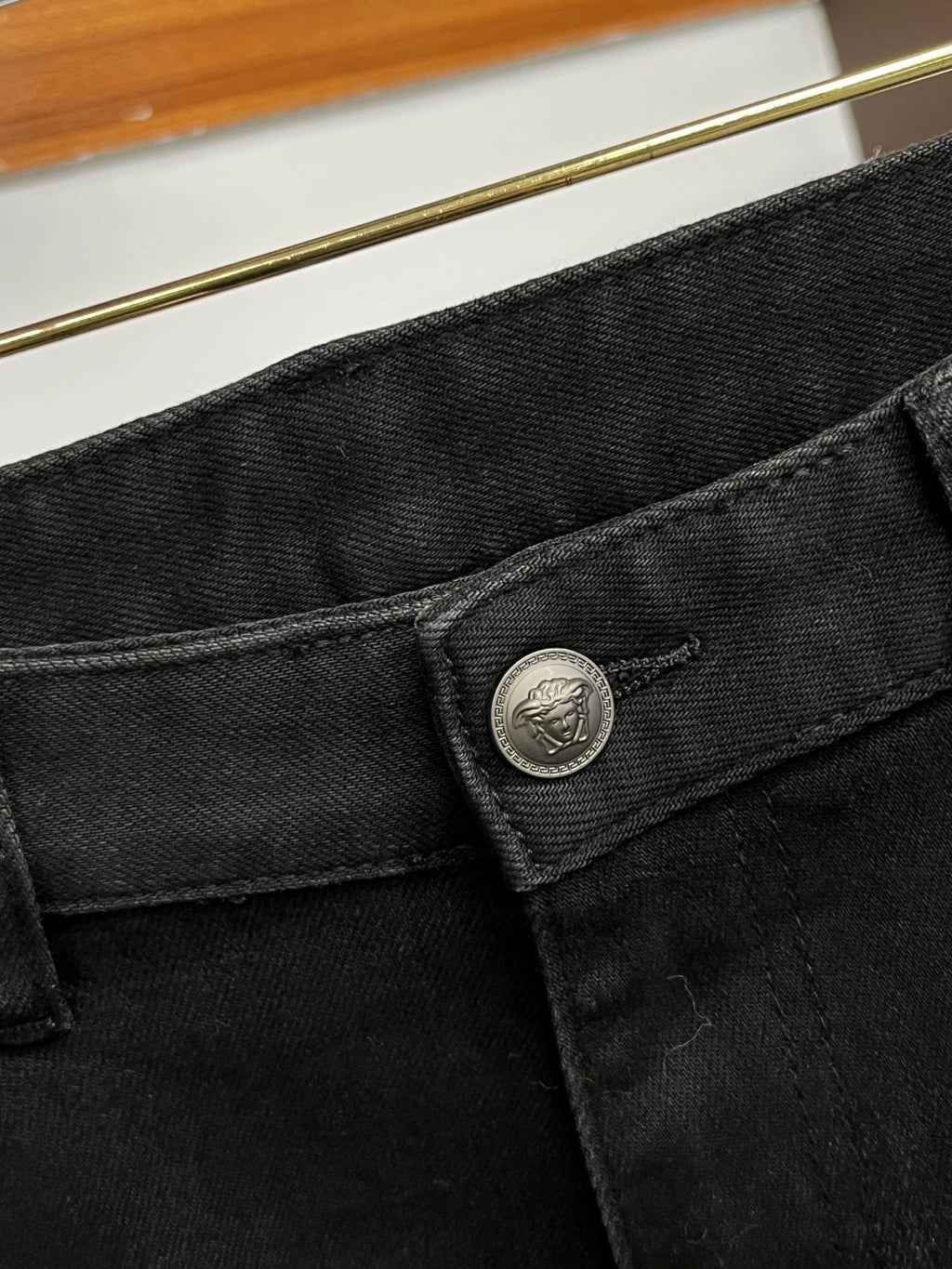 Black denim jeans waistband close-up with round logo button