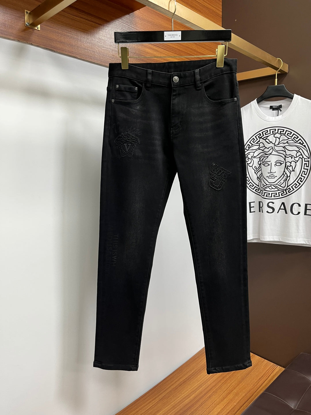 Black Versace jeans on hanger with button fly and front pocket styling