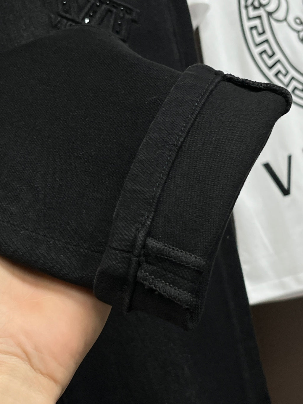 Black denim jeans cuff and inner waistband detail with stitched construction