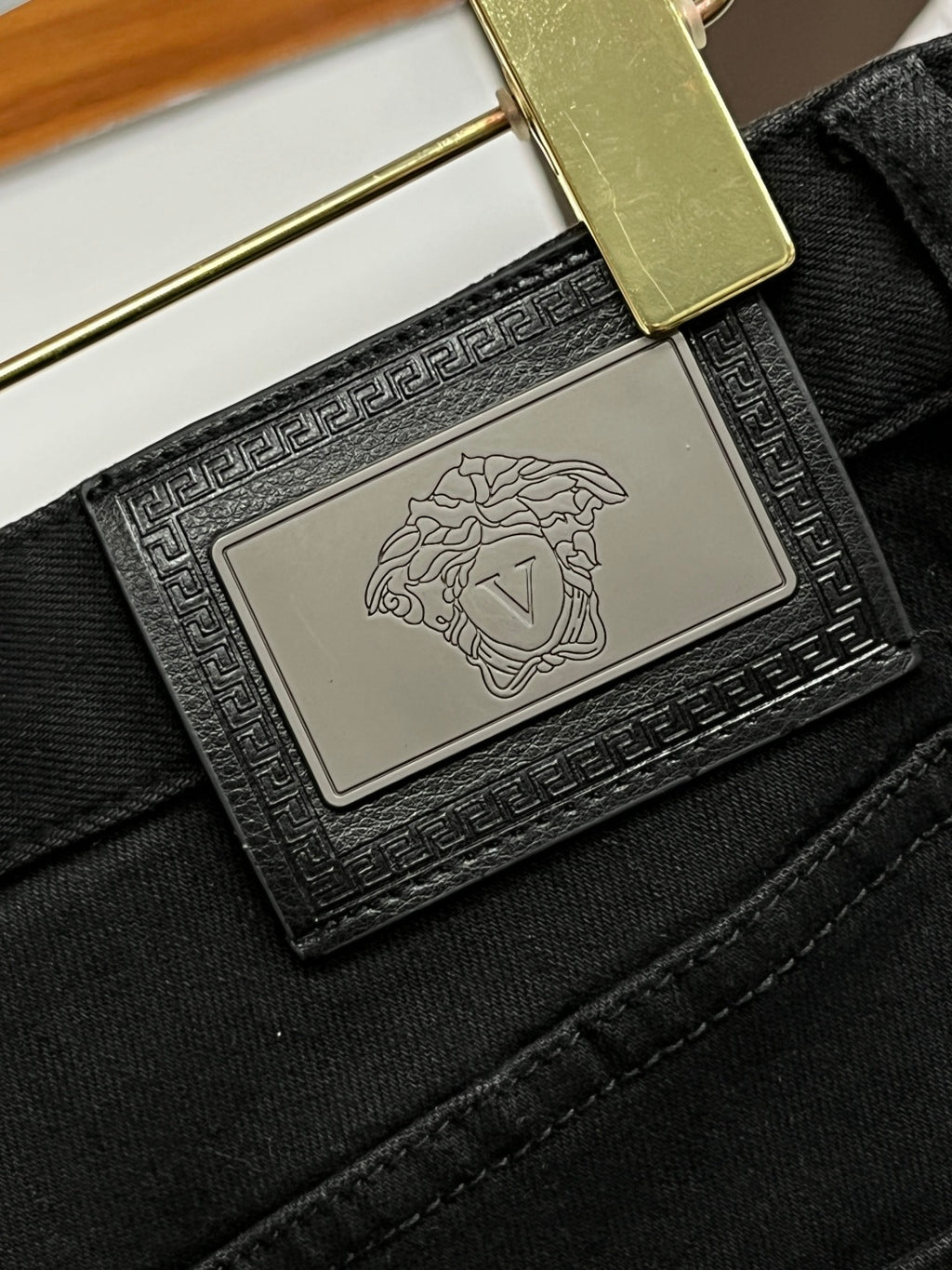 Black denim jeans close-up: rectangular logo patch on waistband