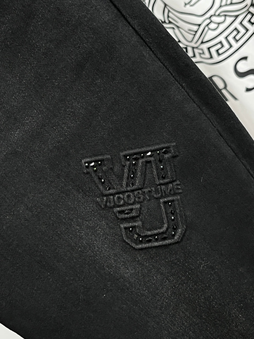 Black denim jeans close-up with studded crest patch