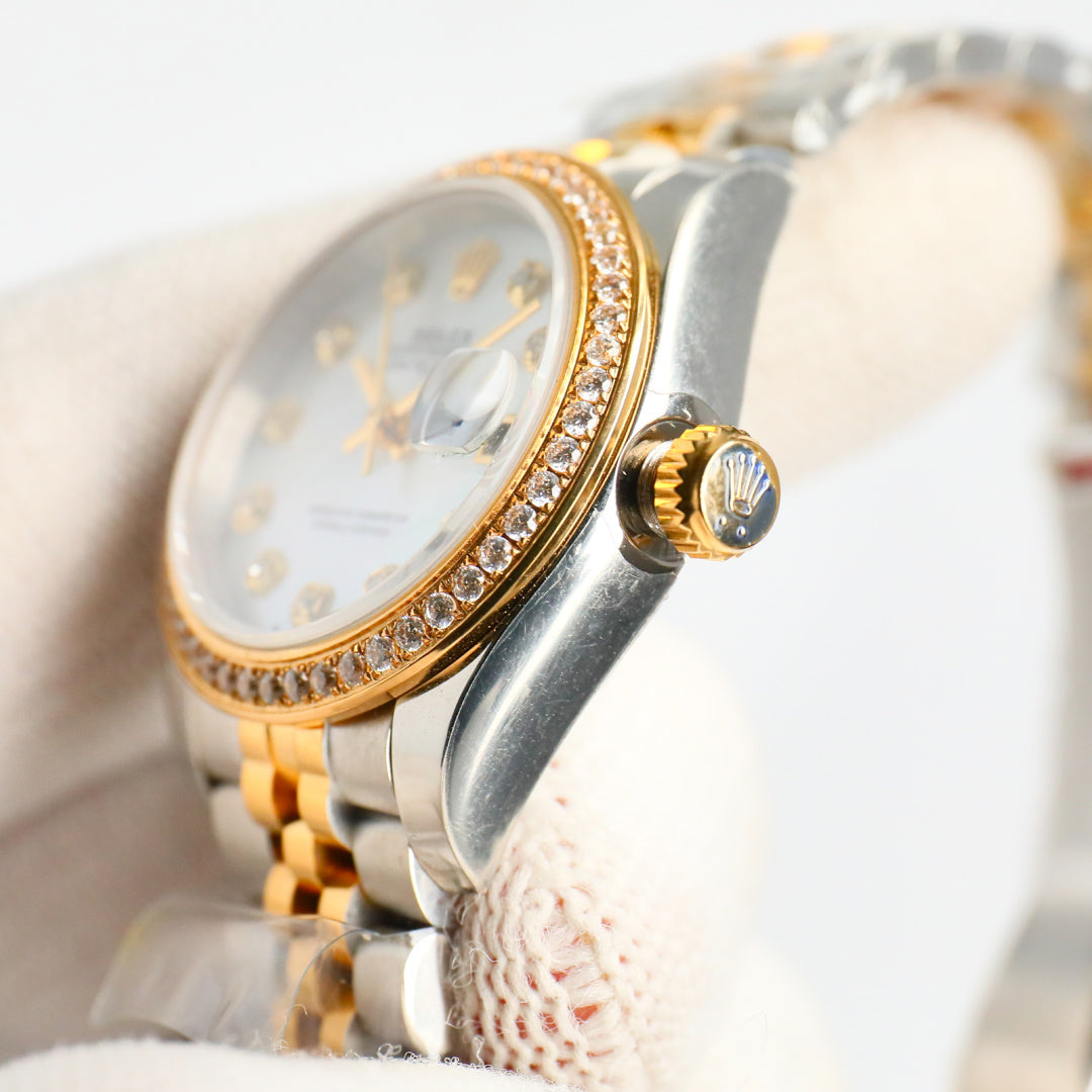 Two-tone wristwatch with diamond bezel, gold crown, and white dial