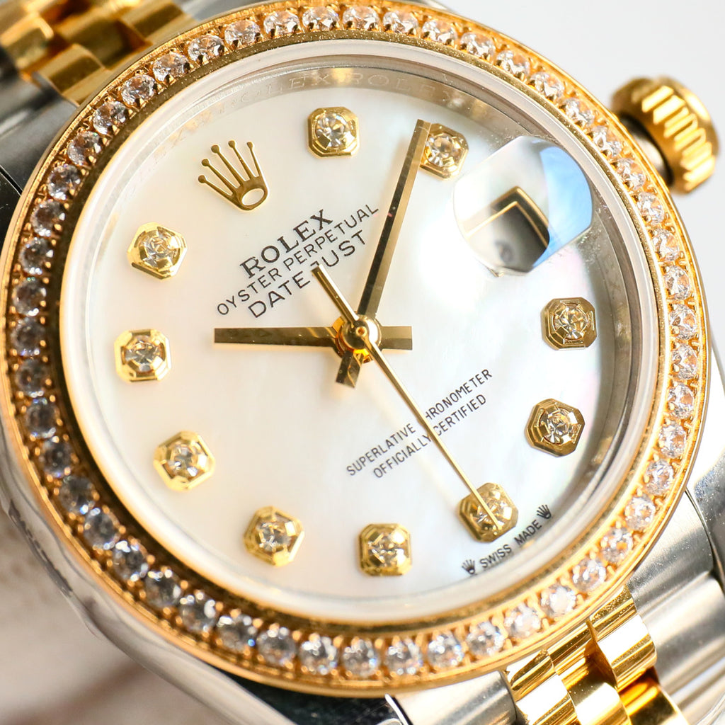 Close-up of two-tone wristwatch face with diamond bezel, gold hands, and markers