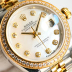 Close-up of two-tone wristwatch face with diamond bezel, gold hands, and markers