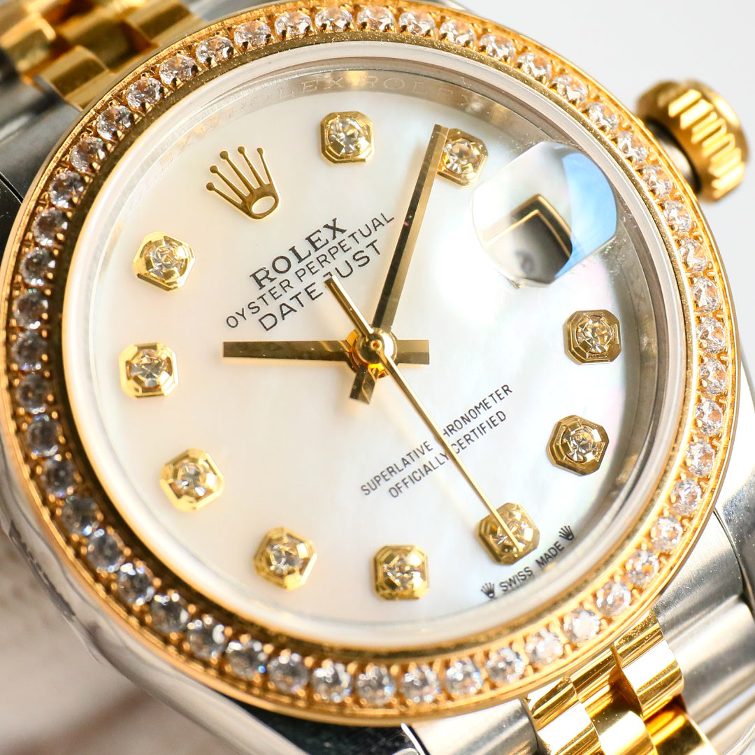 Close-up of two-tone wristwatch face with diamond bezel, gold hands, and markers