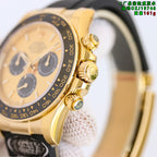 Rolex wristwatch crown and bezel detail, gold-tone case with black rubber strap.