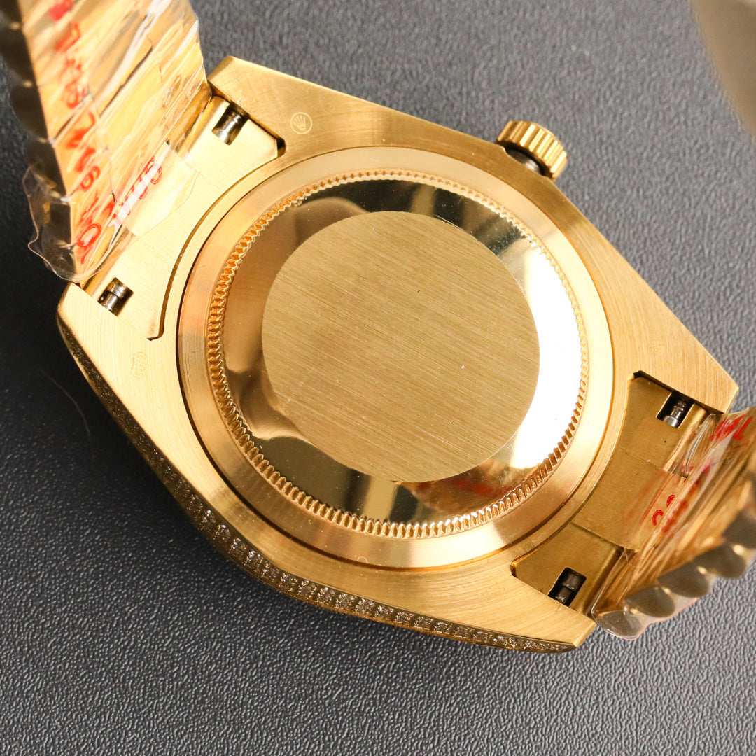 Gold-tone Rolex wristwatch case back with crown detail and diamond accents.