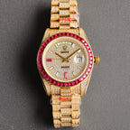 Gold-tone Rolex wristwatch front view with red bezel, diamond markers, and bracelet.