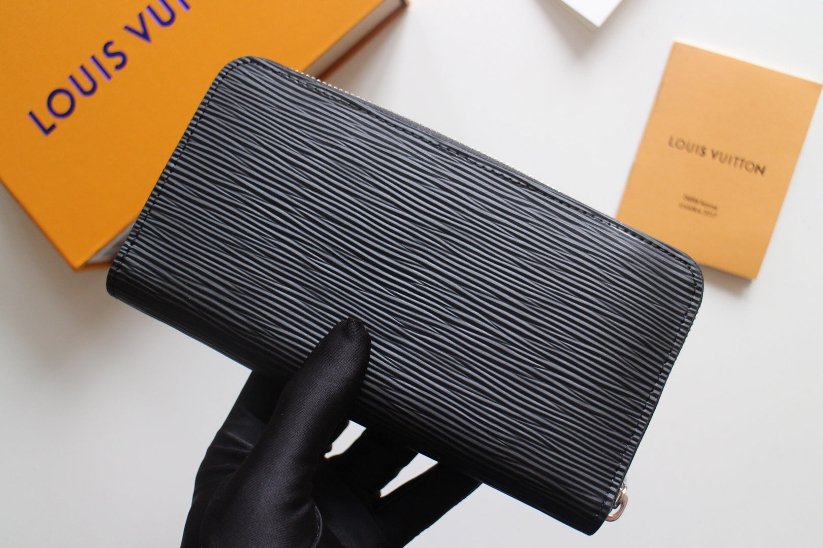 Textured dark leather wallet with front flap fold and visible zipper edge