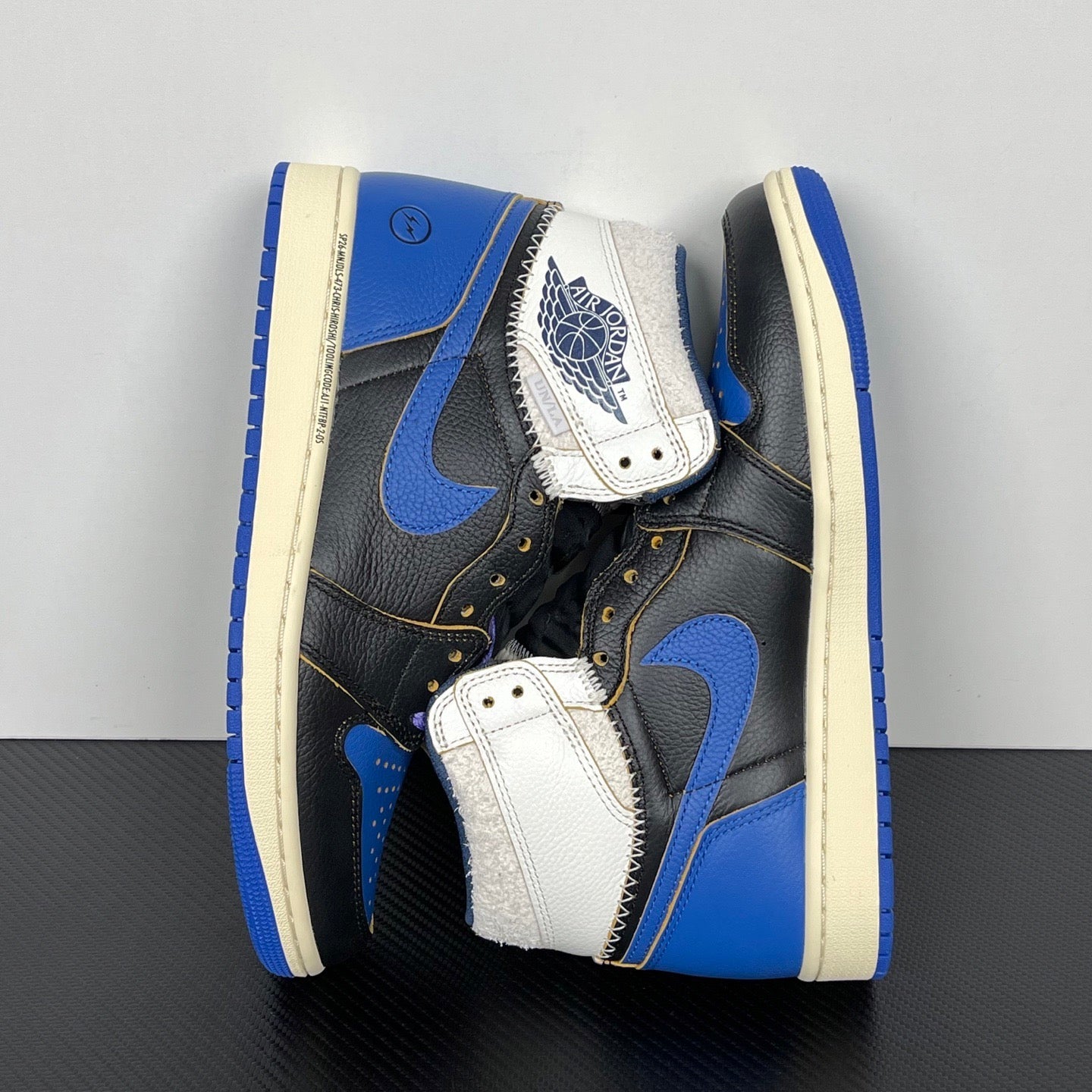 High-top sneakers with white and blue strap detail, black leather upper, cream midsole
