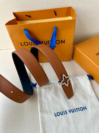Tan belt with dark navy star buckle resting on a pouch and box