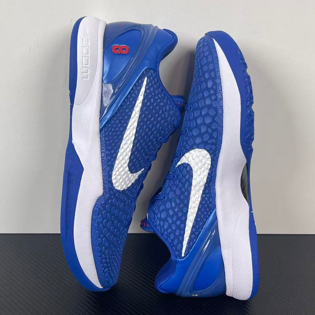 Blue Nike basketball sneaker side view with white heel panels and outsole tread
