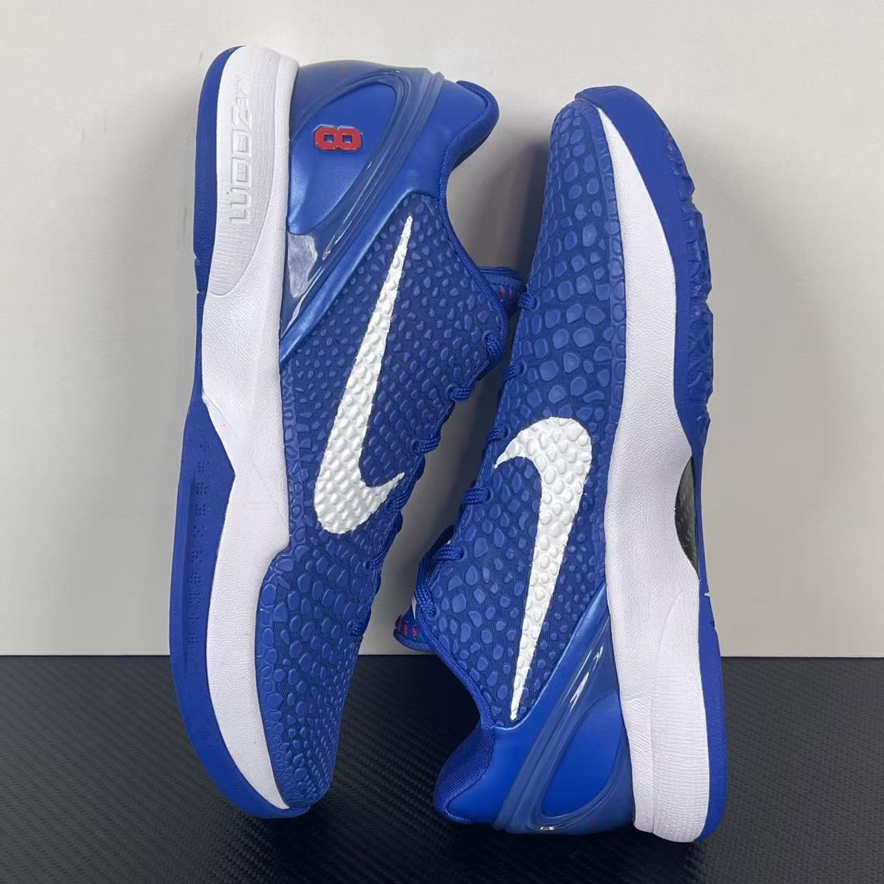 Blue Nike basketball sneaker side view with white heel panels and outsole tread