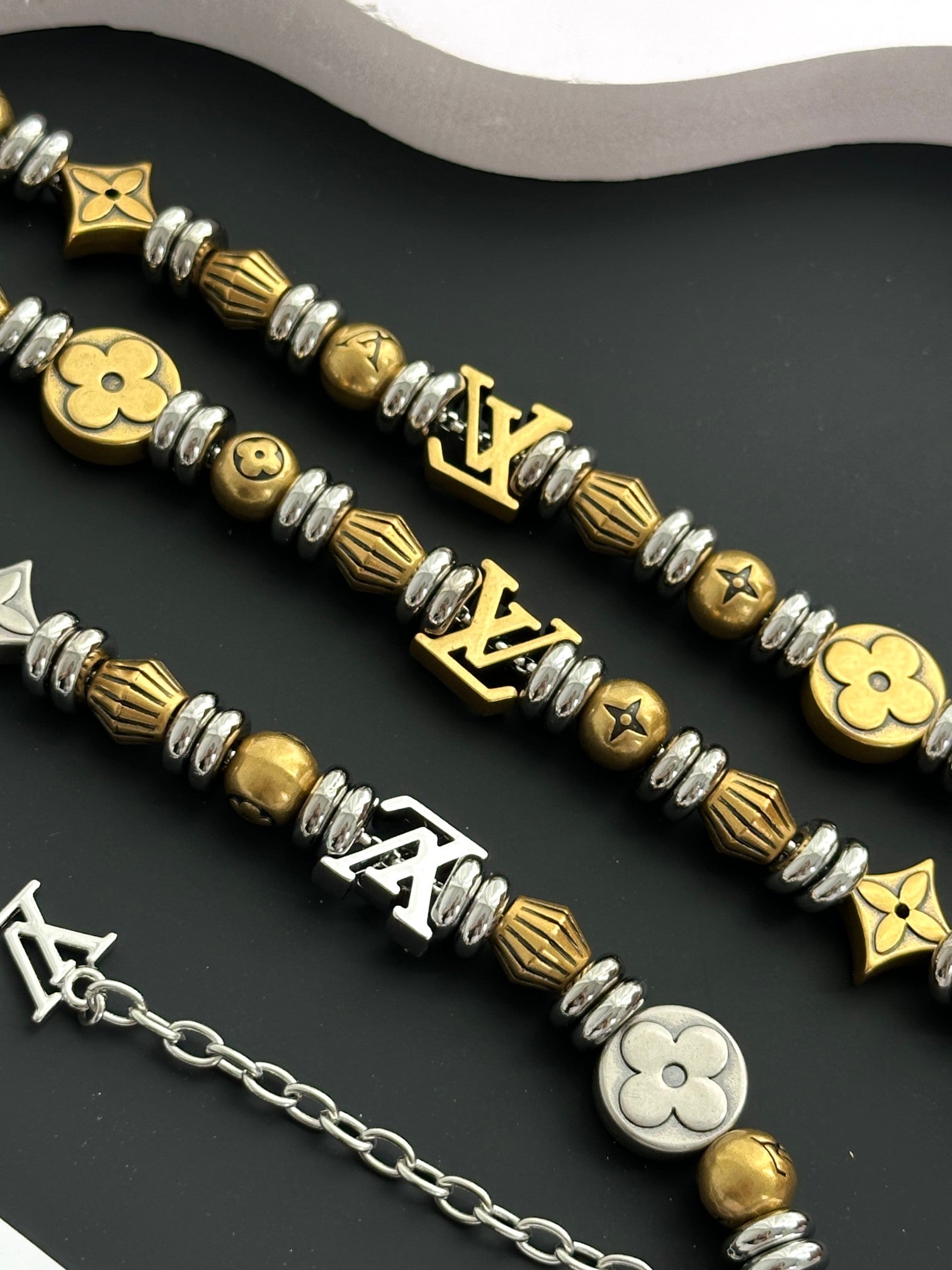Close-up of gold and silver charm bracelets with flower and star emblems