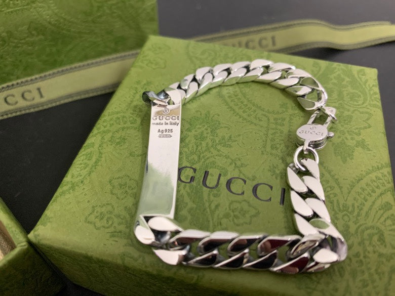 Silver chain bracelet with Gucci charm and white leather panel, shown from above