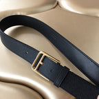 Dark textured leather belt with gold buckle lying across surface