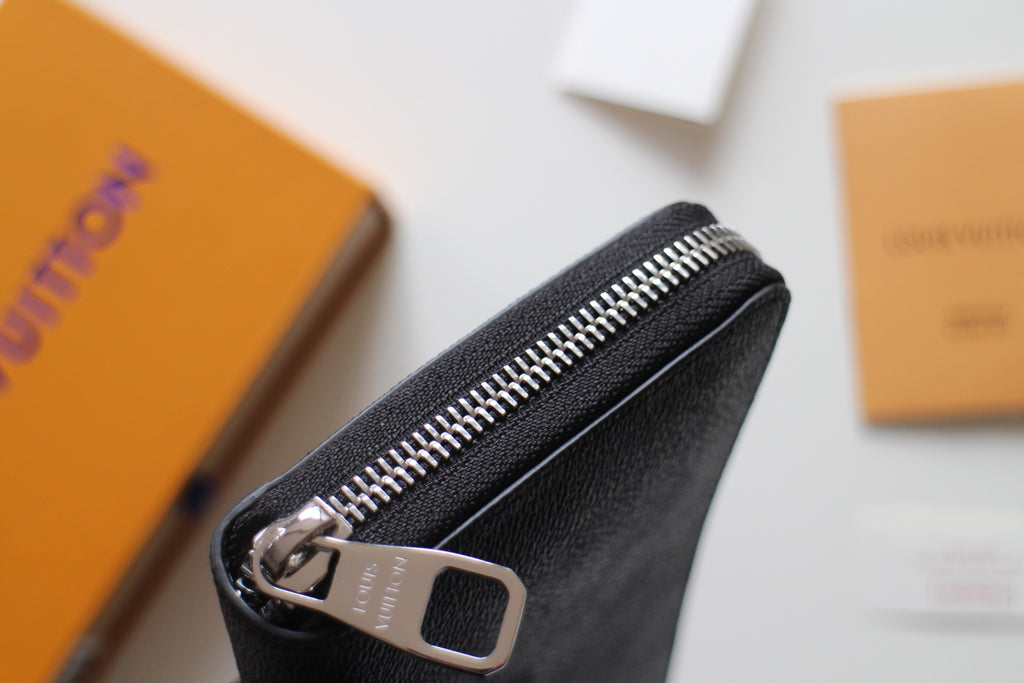 Small Louis Vuitton zip wallet corner with silver zipper and dark textured leather trim.