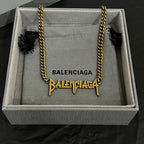 Balenciaga gold chain necklace inside gray gift box with branded tag and charms