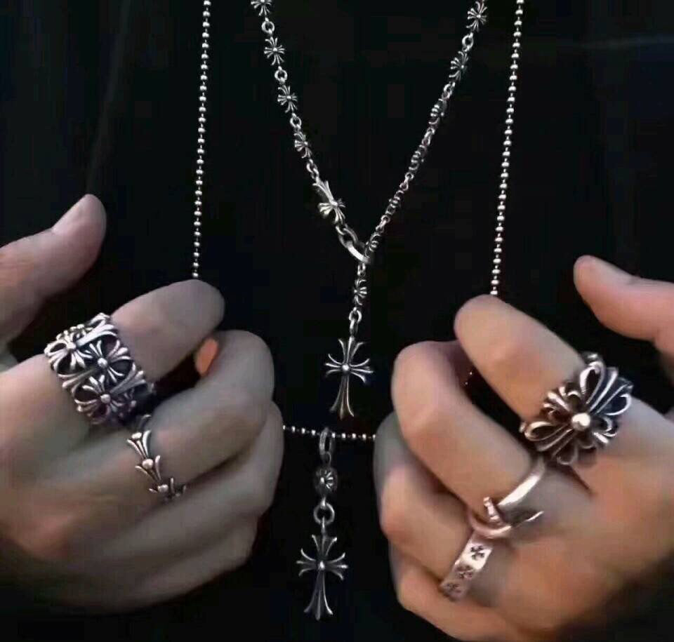 Silver-tone cross emblem rings held in hands, with a matching chain necklace
