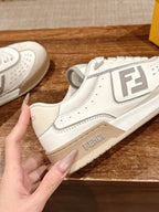 Cream white unisex sneaker with Fendi logo on side, hand holding shoe