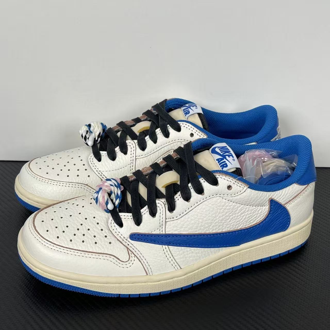 Pair of white and blue sneakers with black laces and blue swoosh on sides