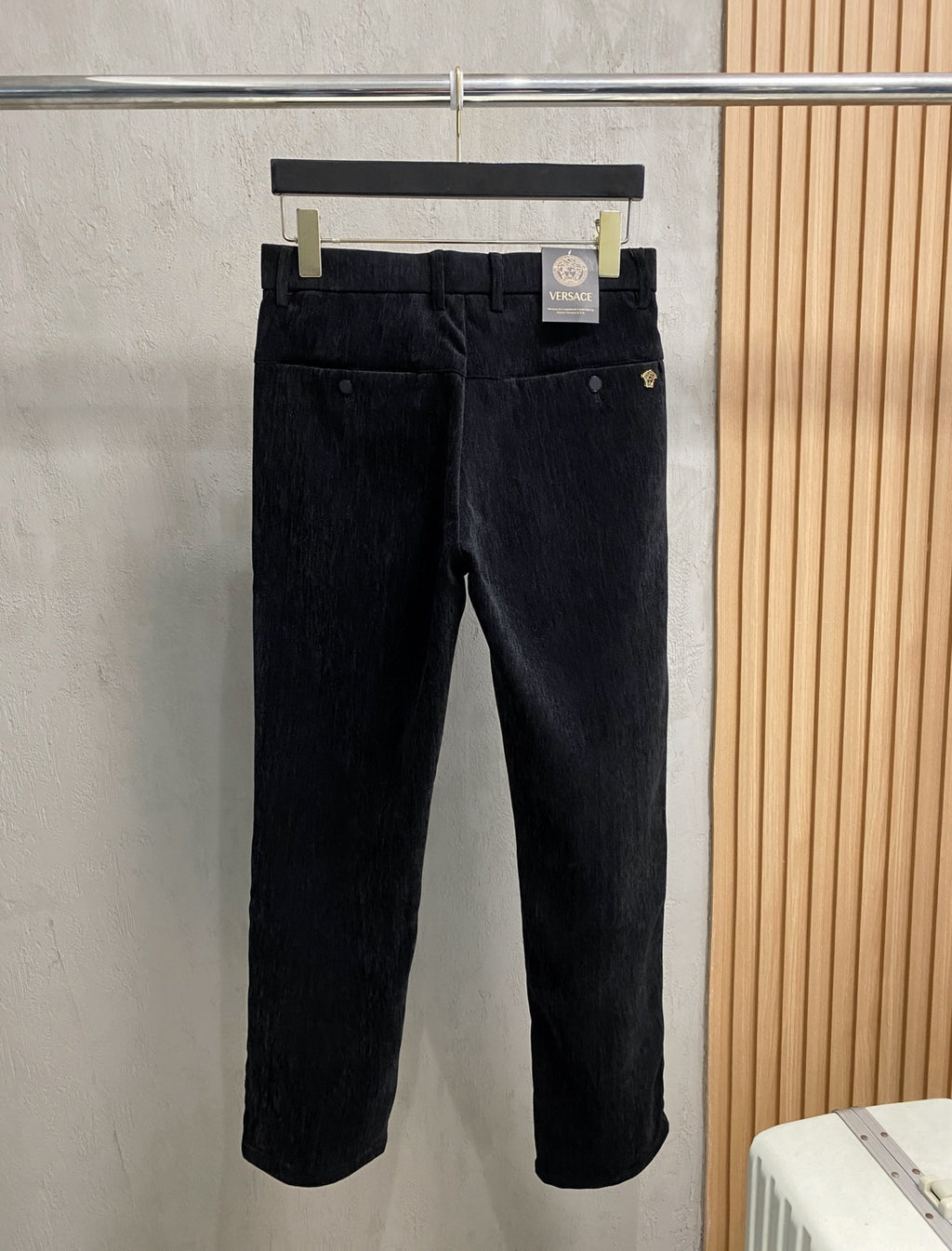 Black trousers with belt loops, front button, and side pockets on hanger
