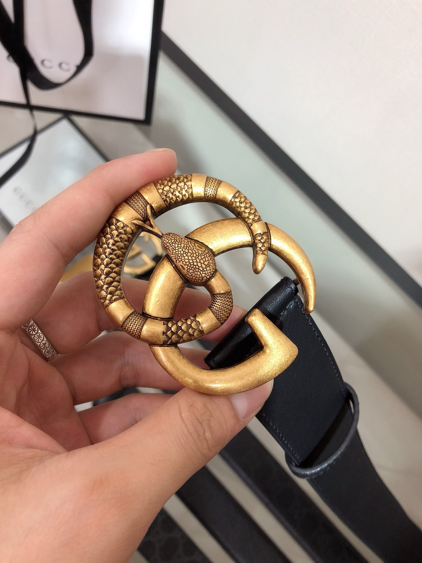 Belt buckle close-up: gold G-ring clasp on black strap