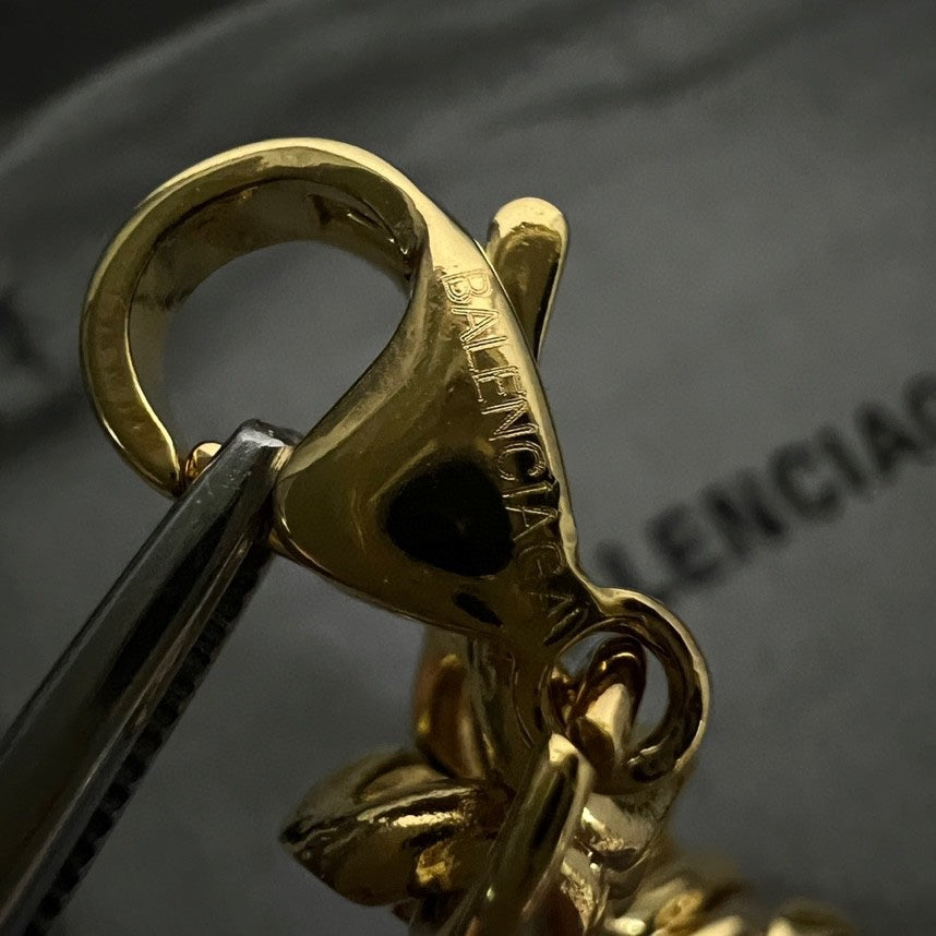 Balenciaga logo clasp detail on gold tone chain bracelet, with ring attachment