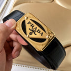 Black leather belt with gold Prada buckle, held in hand for detail