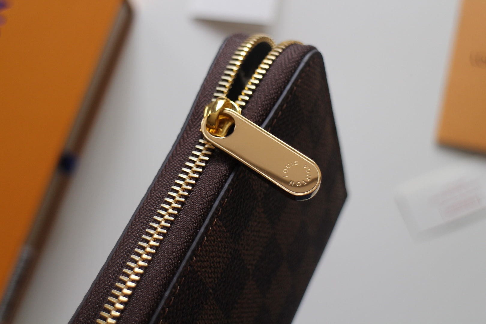 Louis Vuitton small bag front with gold zipper pull on Damier canvas.