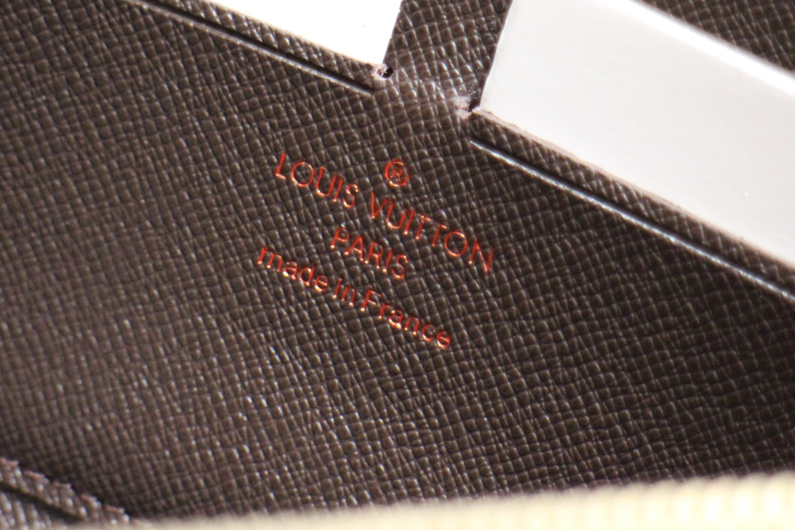 Louis Vuitton small bag embossed logo on textured leather panel.