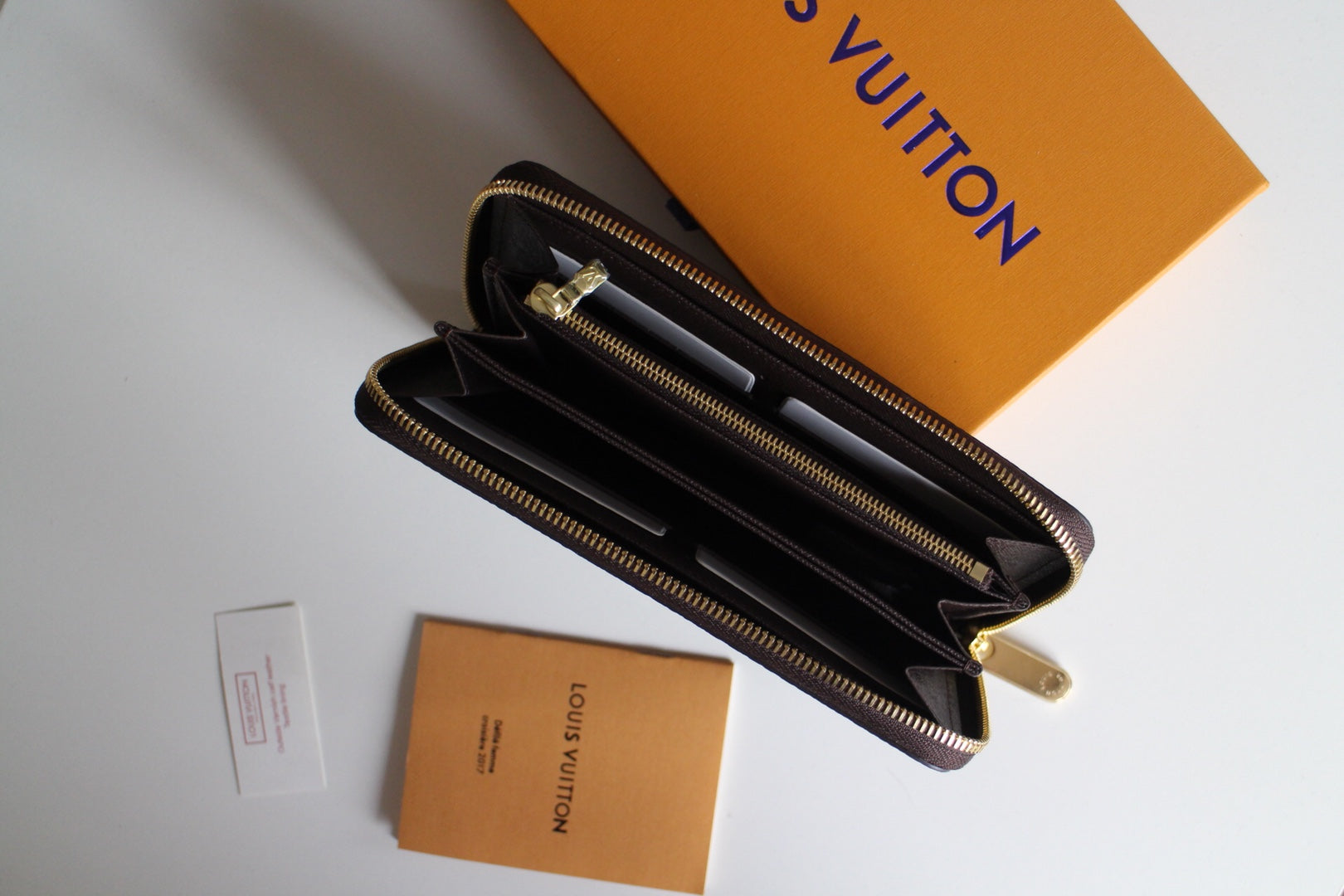 Louis Vuitton small bag opened to dark interior with multiple compartments and zip.