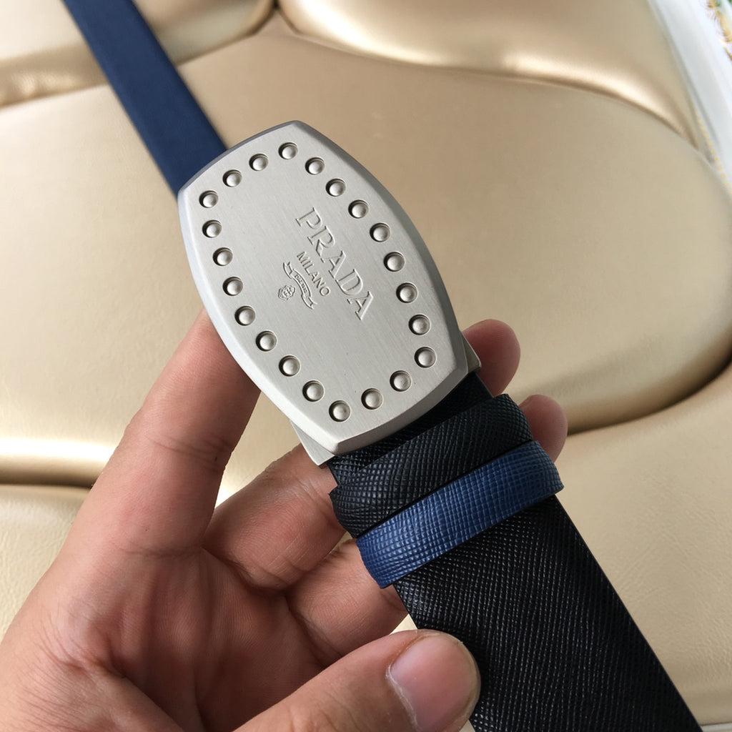 Navy belt with silver studded Prada buckle held up, black and blue strap