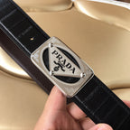 Prada belt close-up: dark leather strap with silver logo plaque buckle
