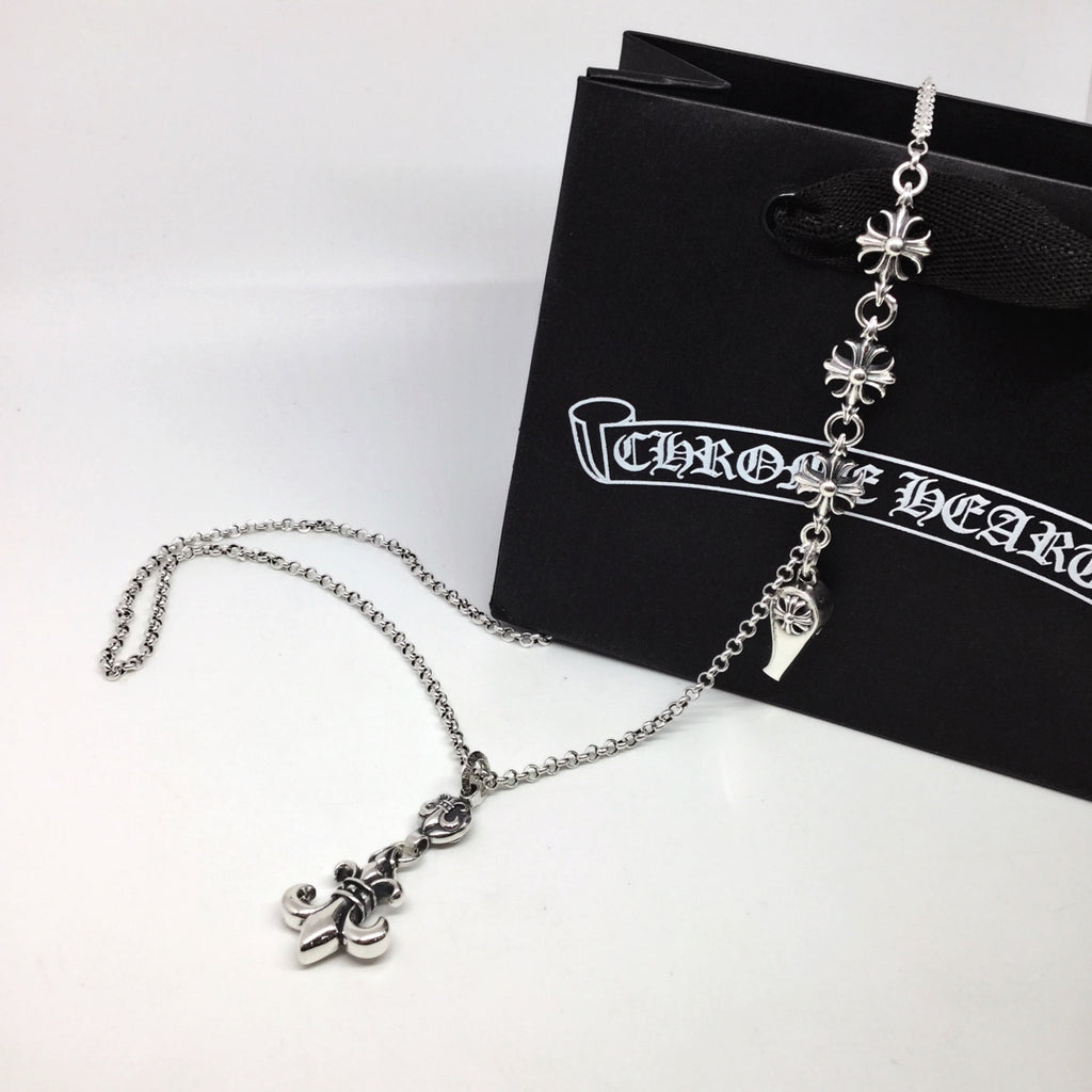 Silver chain necklace with fleur-de-lis and charm dangles, on black pouch