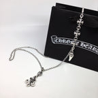 Silver chain necklace with fleur-de-lis and charm dangles, on black pouch