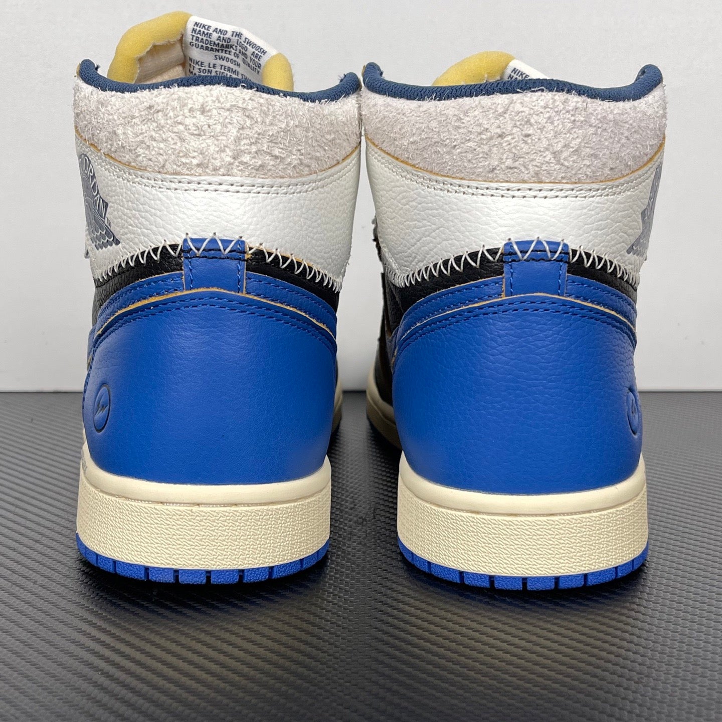 High-top sneakers back view with white and blue heel panels, black upper, cream midsole