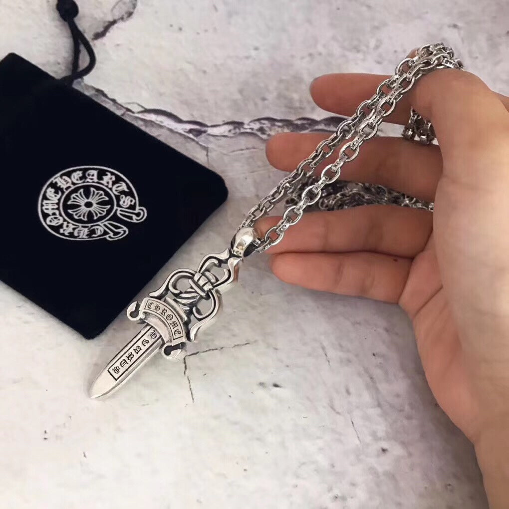 Chrome accessories dagger pendant necklace with silver chain, held in hand