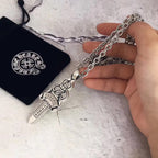 Chrome accessories dagger pendant necklace with silver chain, held in hand