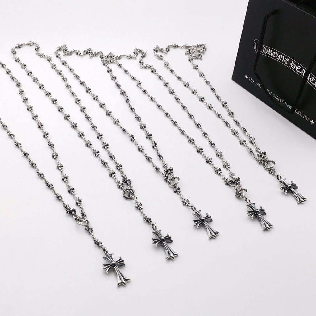 Set of silver-tone cross charm chain necklaces arranged on a white surface