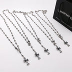 Set of silver-tone cross charm chain necklaces arranged on a white surface
