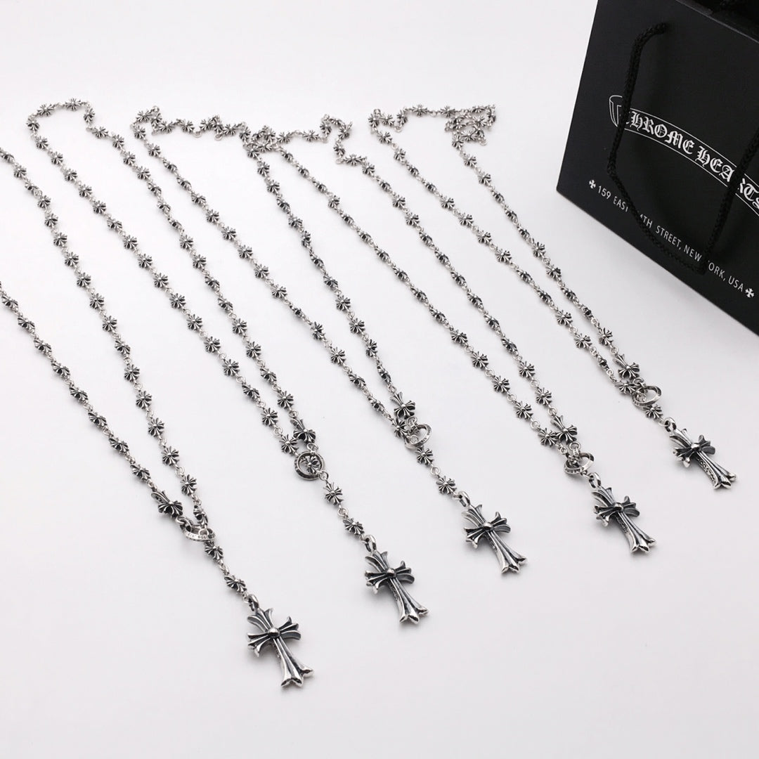 Set of silver-tone cross charm chain necklaces arranged on a white surface