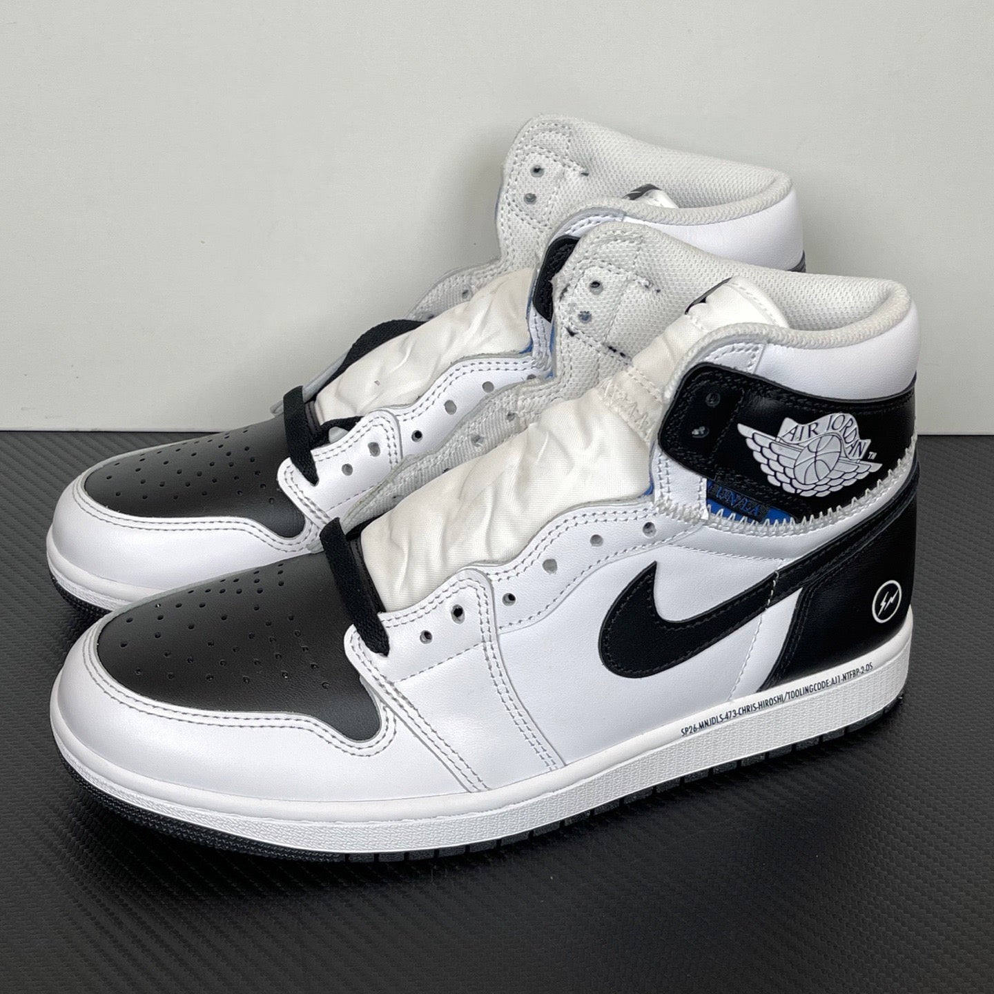 Three-quarter view of white and black high-top sneakers with black Swoosh and wing logo