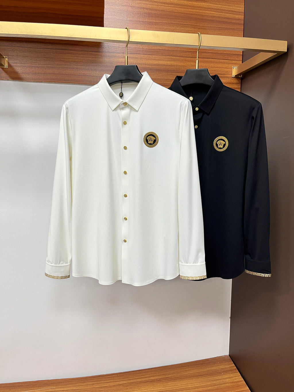 White and dark button-up shirts side by side with point collars and gold emblem patches