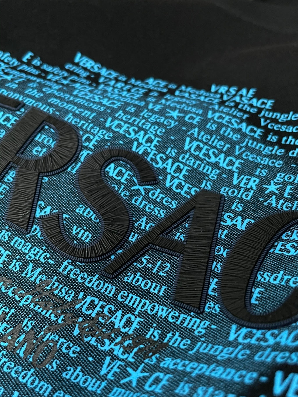 Black crewneck sweatshirt close-up of blue typographic graphic on chest