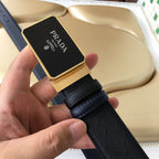 Prada belt detail: black textured strap with gold-edged logo plaque buckle