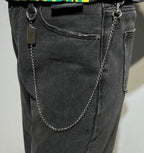 Balenciaga chain belt charm with metal tag and ring details on dark denim