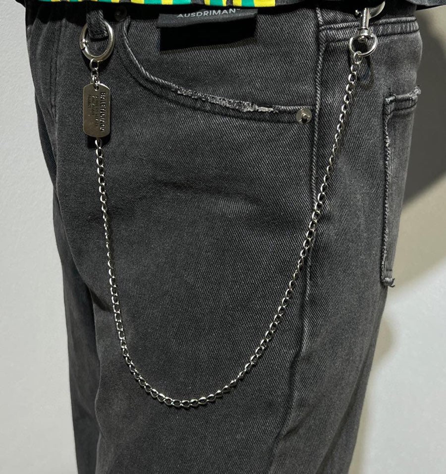 Balenciaga chain belt charm with metal tag and ring details on dark denim