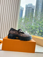 Side profile of monogram slip-on shoes with buckle strap, brown pattern and black soles